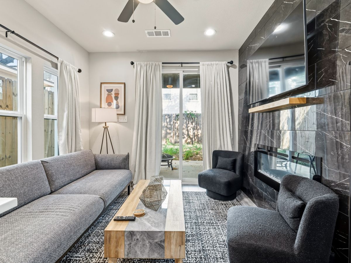 Sink into plush seating in your bright, modern living space, where natural light pours through sliding doors to your private patio. A striking marble accent wall and stylish furnishings create an inviting retreat for relaxation.